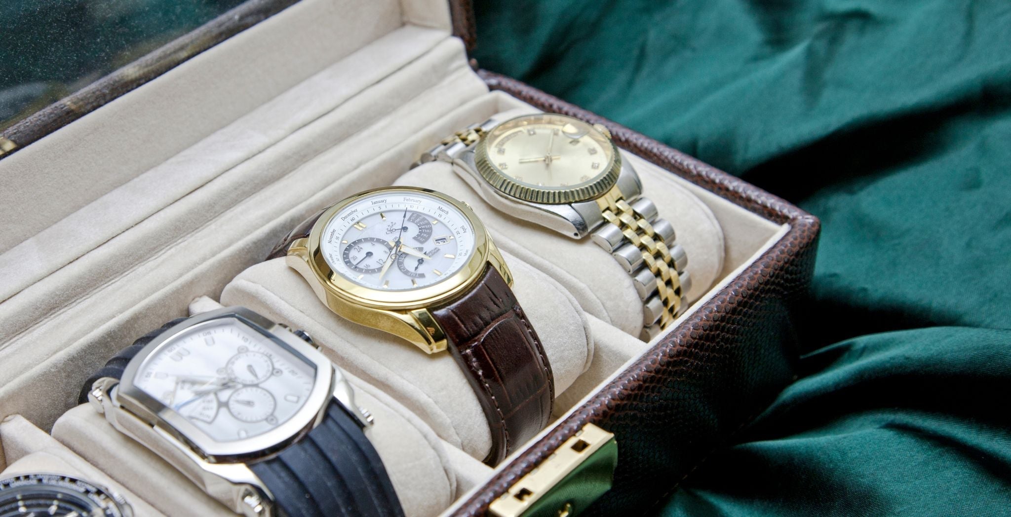 Luxury watches displayed in a watch case featuring leather straps and metal bracelet bands, showcasing classic and premium timepiece styles.